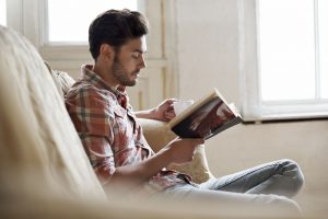 man-sitting-on-sofa-reading-book